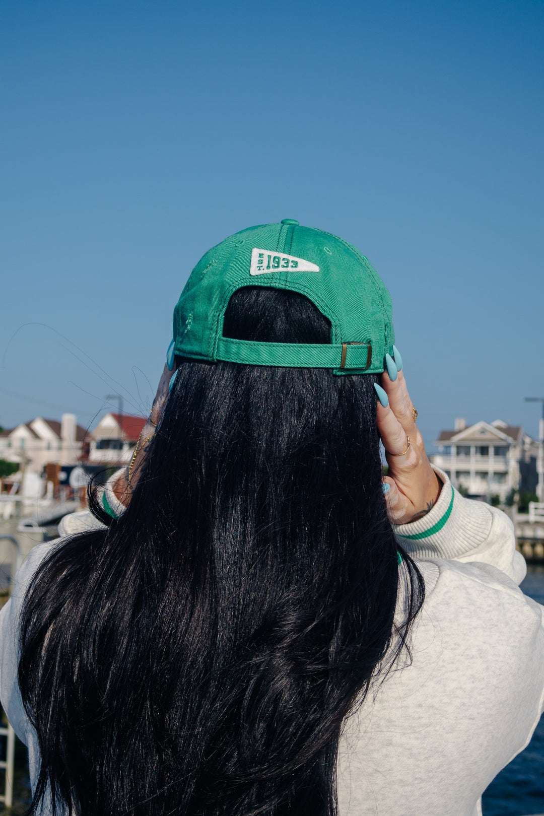 A woman outdoors wearing a kelly green Philadelphia Eagles distressed baseball cap and a light gray sweatshirt with green &