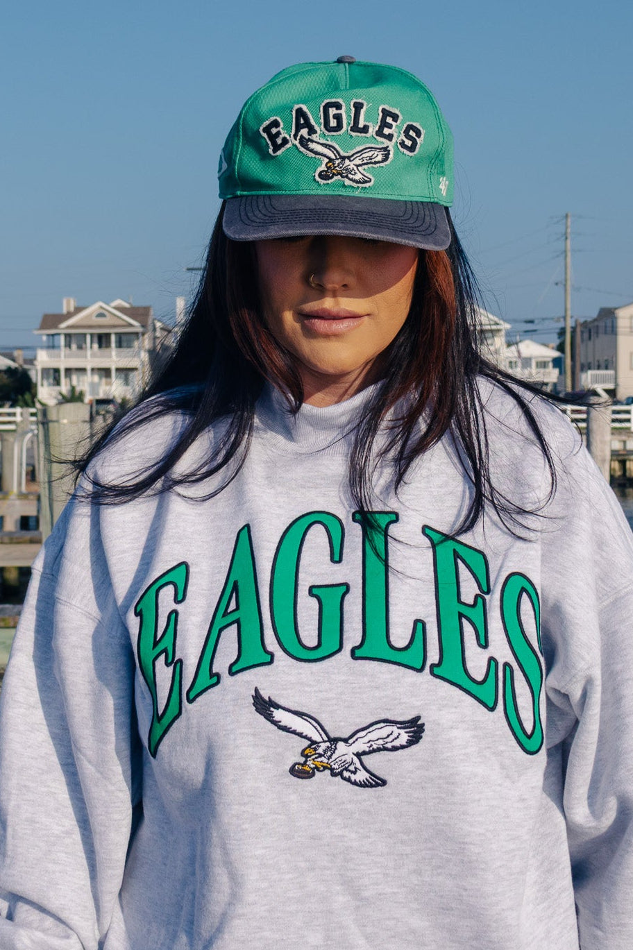 A woman wearing a light gray heather sweatshirt with &