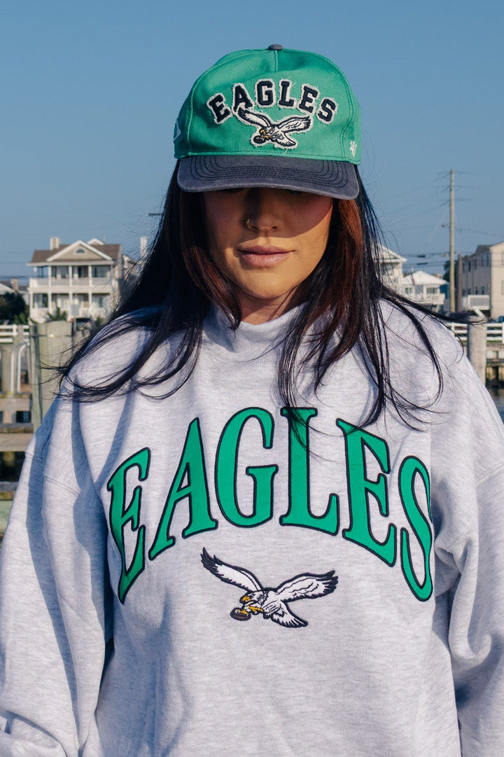 A woman wearing a light gray heather sweatshirt with &